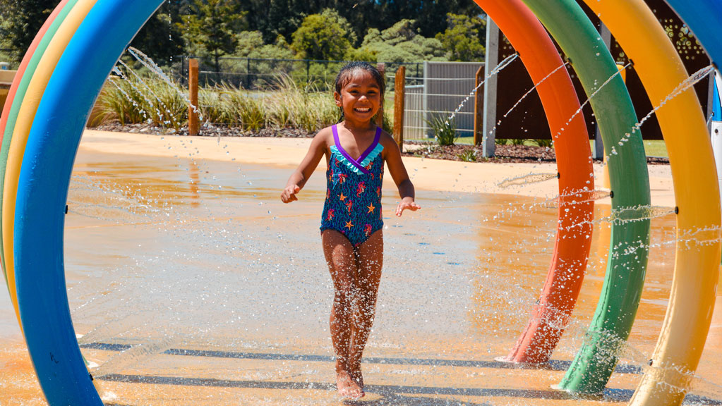 child running through water rings in zero depth splash park