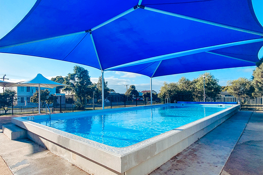 Bright Blue shade sail over West Beach Primary School pool, ready for swimming lessons.